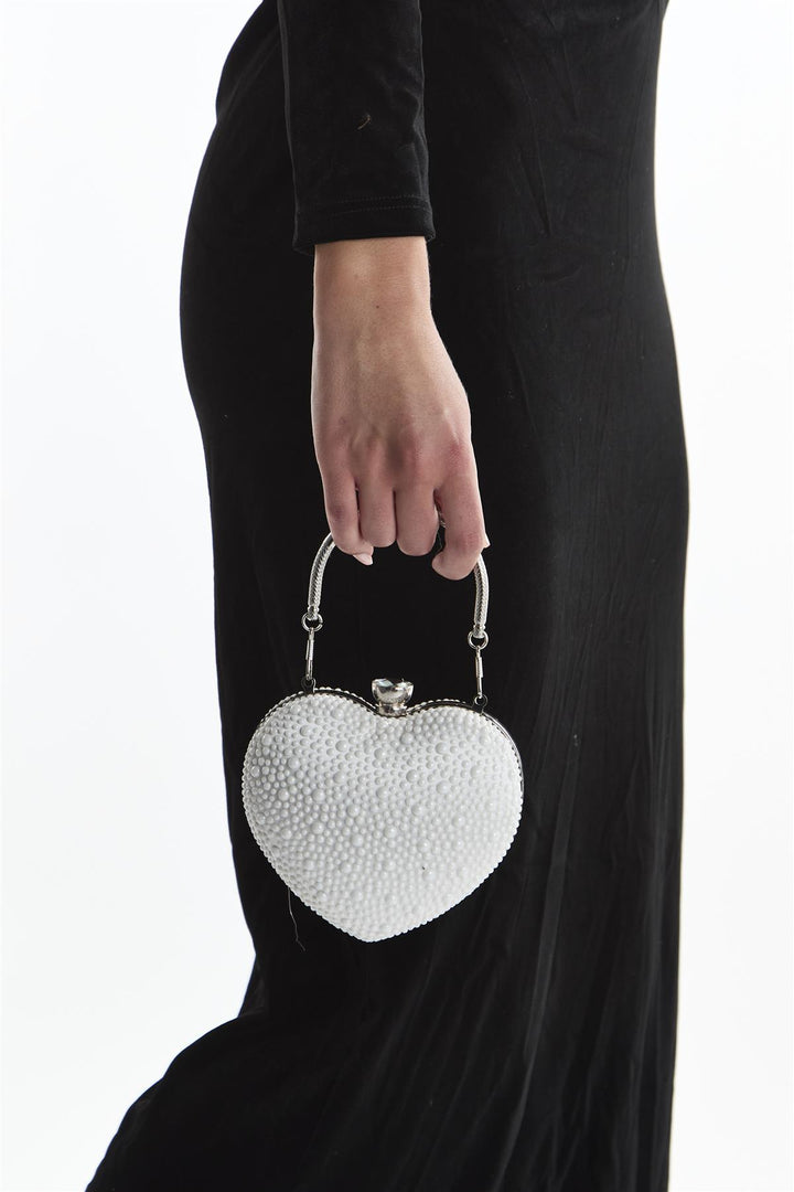 Heart-shaped beaded handbag held by a person wearing a black dress.