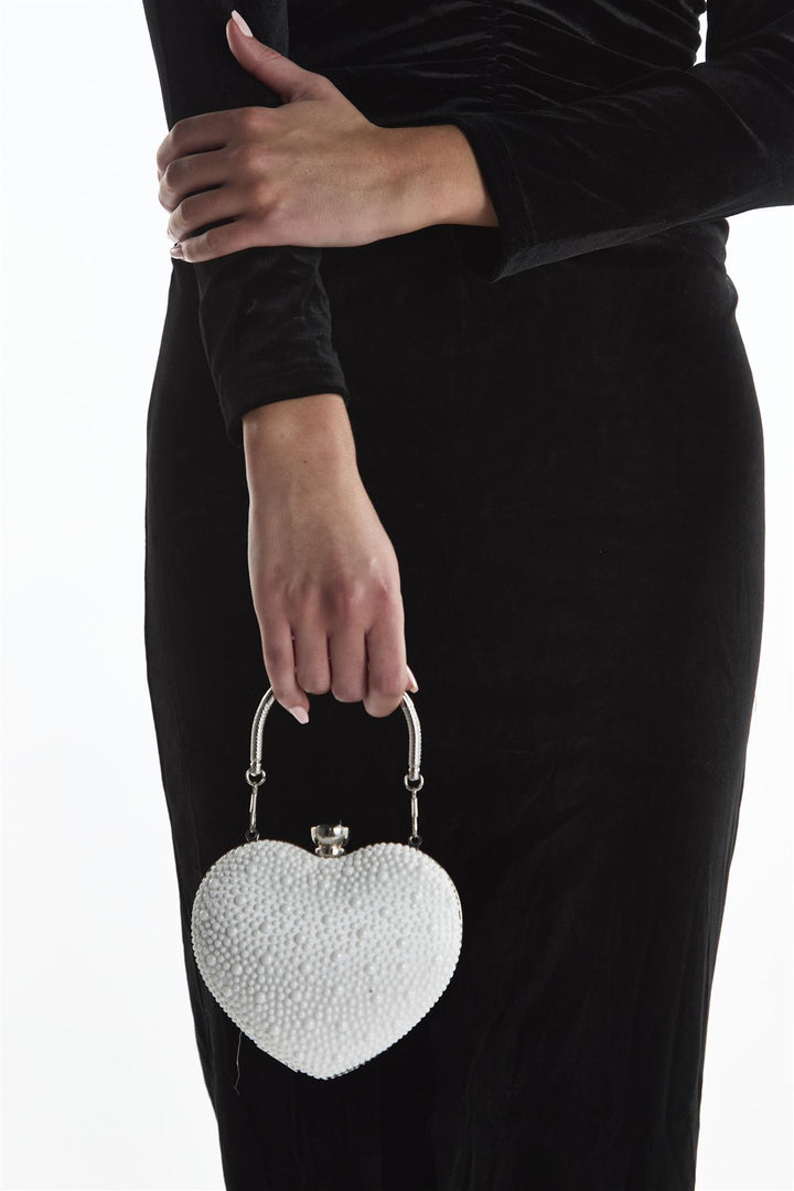Heart-shaped beaded clutch held by a person wearing a black dress on a white background
